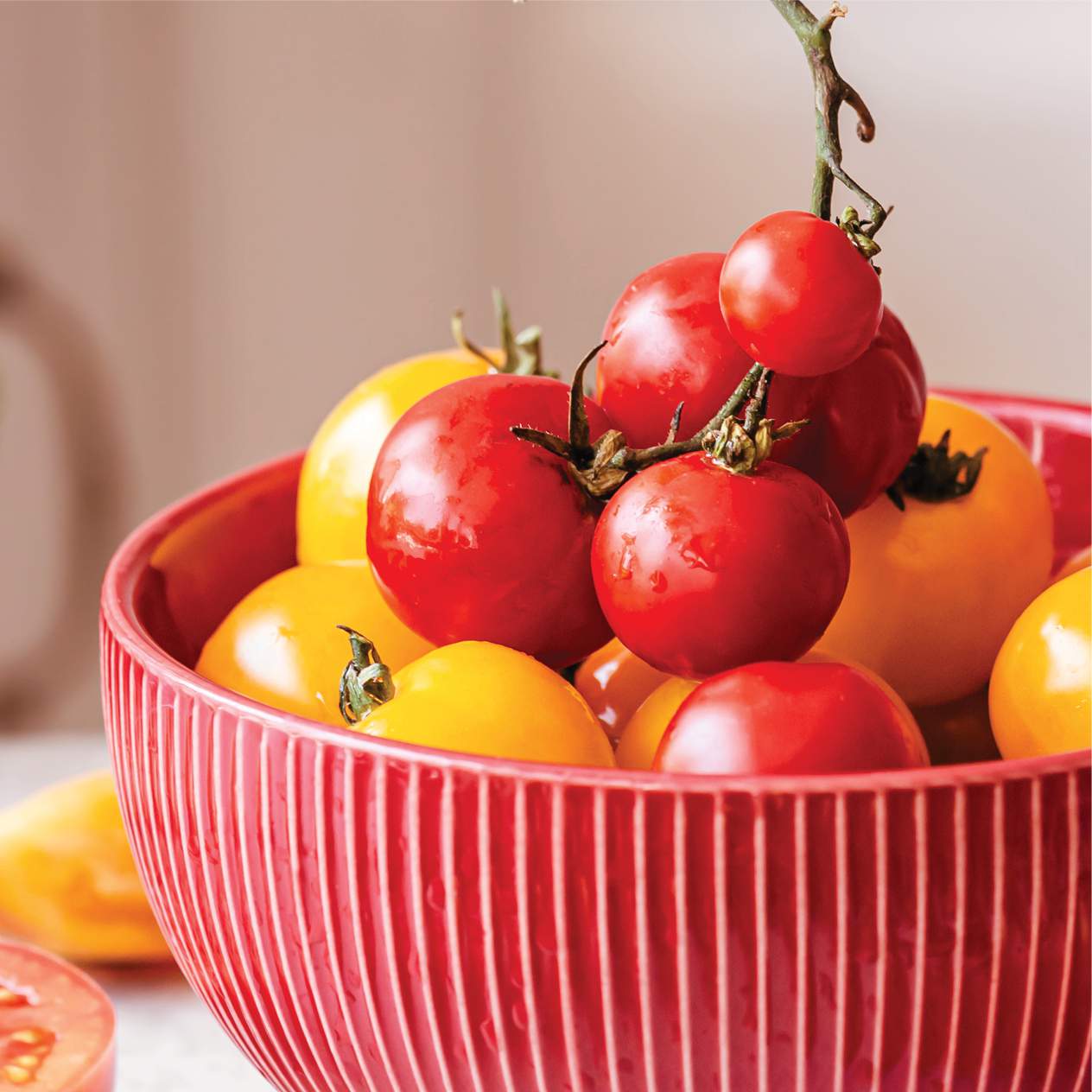 Red bowl with fresh, ripe yellow and red tomatoes for healthy eating.