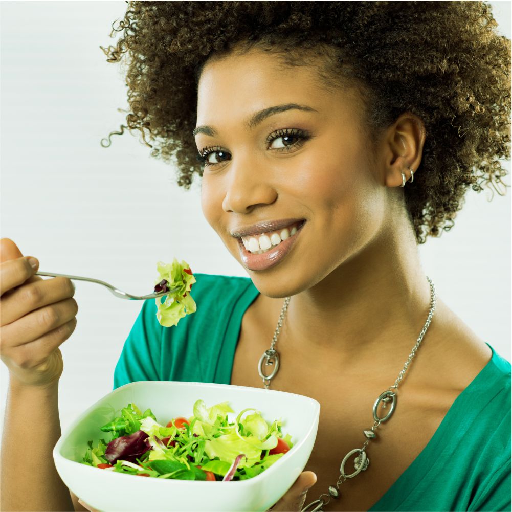 A woman eating a fresh green salad.